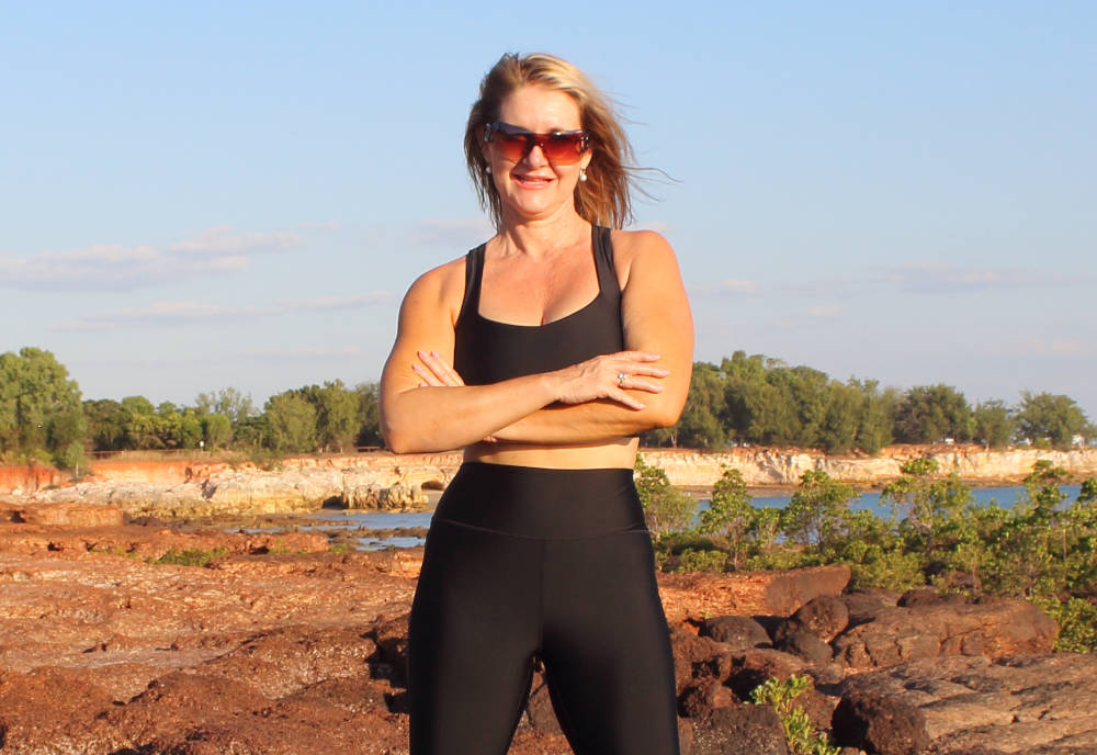 healthy woman wearing black swim gym wear on beach in Darwin Australia