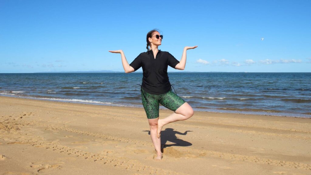 women meditating on beach wearing swimwear BAN_1060