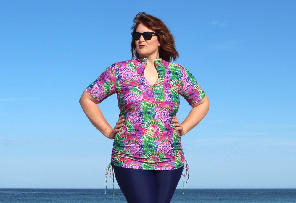plus size women wearing colourful pretty swim shirt on beach with uv protection banner