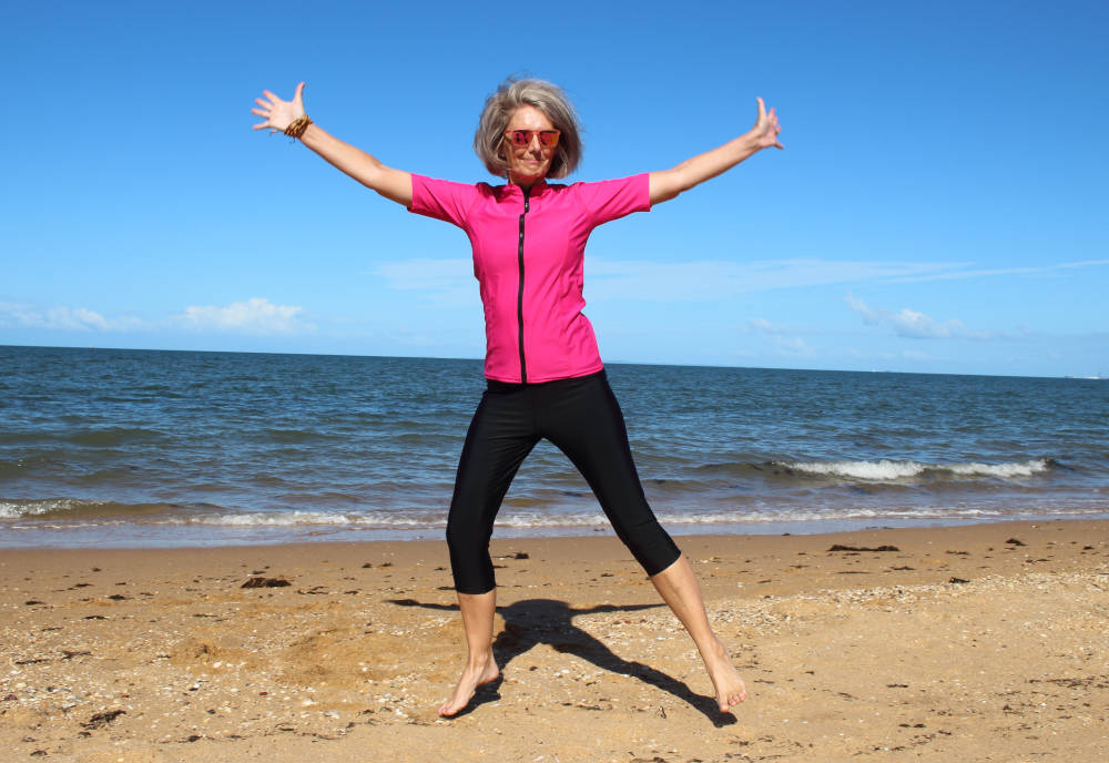 Banner - woman jumping on beach wearing sun safe swimwear