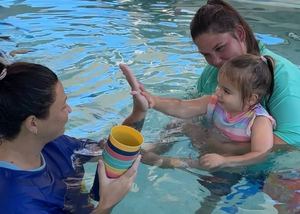 mother with small child and swim instructor swim tikes learn to swim swim school Brisbane mum and baby swimming classes